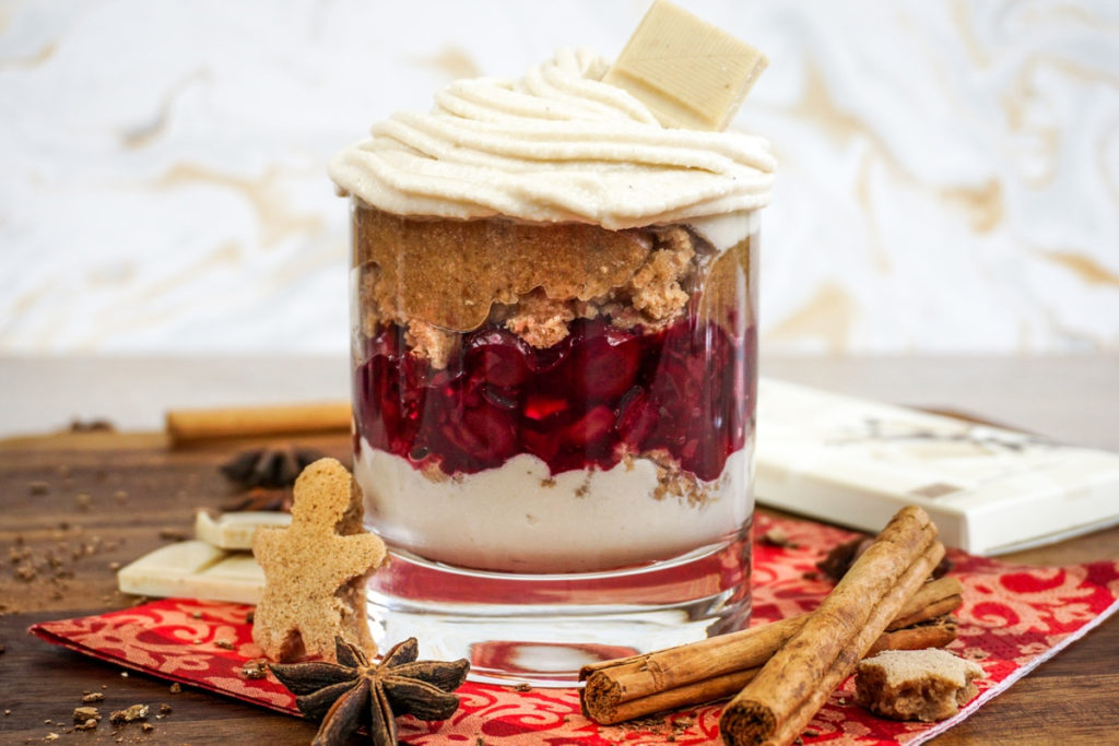 Ein veganes, weihnachtliches Schichtdessert mit weißer Schokoladencreme, selbstgemachten Spekulatiuskeksen und Kirschen